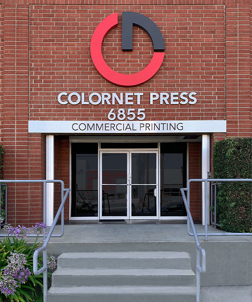 image of the front of the building Colornet Press Commercial printer showing a brick building with steel awning and glass doors